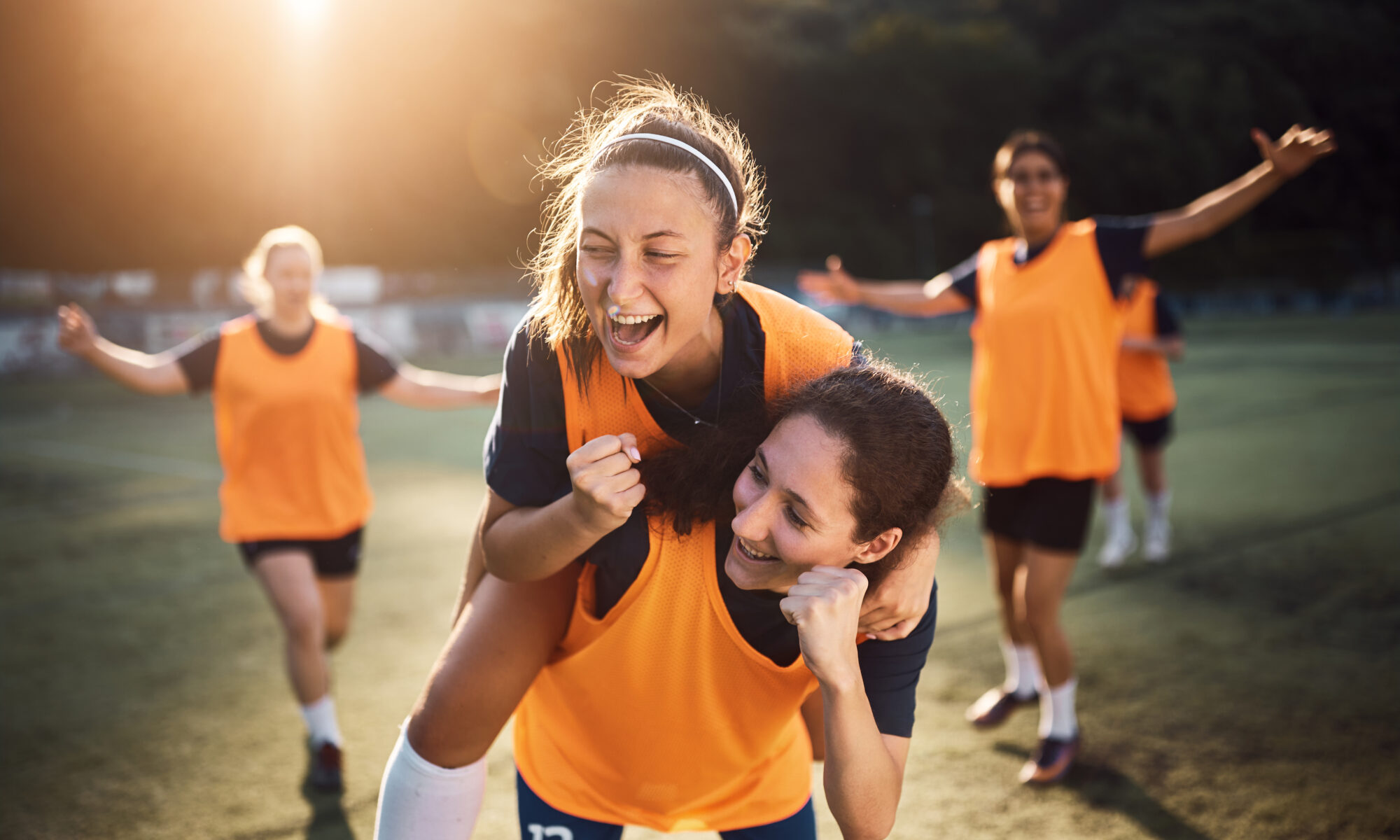Счастливые женщины-игроки празднуют гол во время футбольного матча на стадионе,