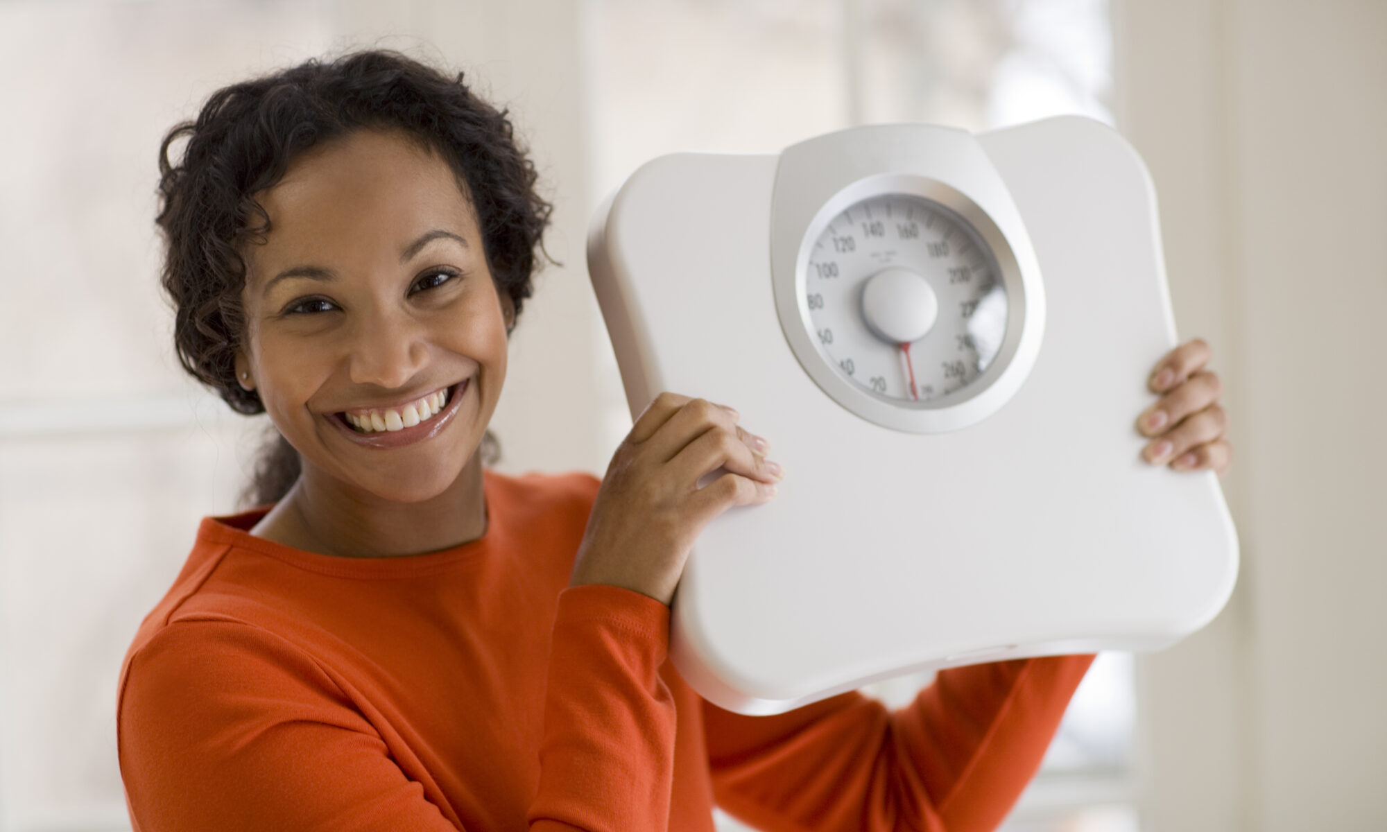 Счастливая чернокожая женщина держит весы
